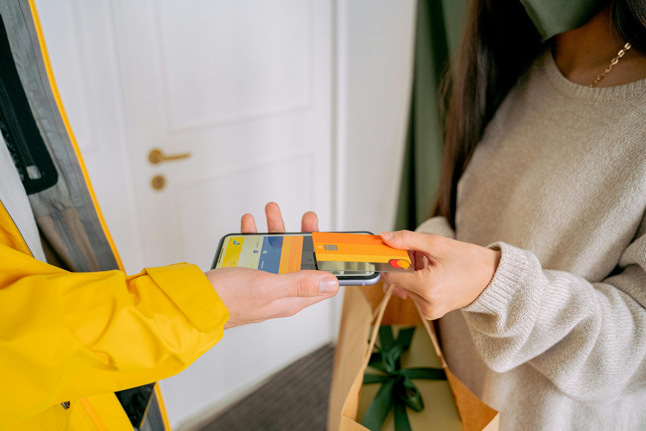 A close-up view of contactless payment transaction using a mobile phone and credit card indoors.